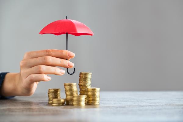 Small red umbrella over pile of coins