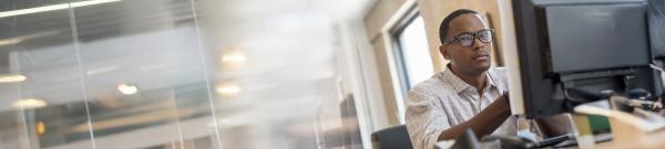 a Black man looking intently at a computer monitor