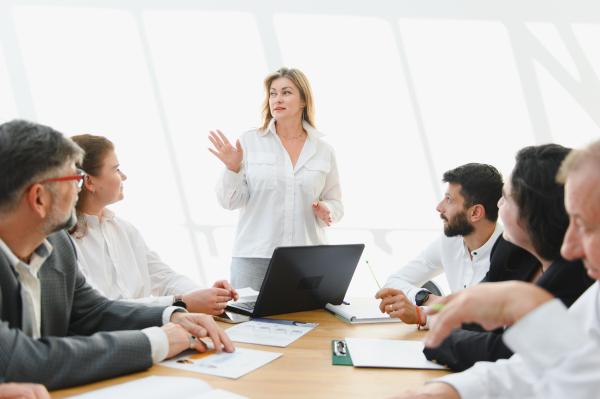 Businesswoman gesturing while leading a team meeting in a brightly lit office
