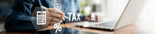 A man sitting at a desk with a laptop, with digital images of TAX, a calculator, and a percentage icon floating in front of the screen