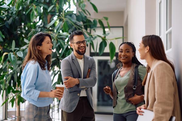 Group of four young, professional, people talking and laughing