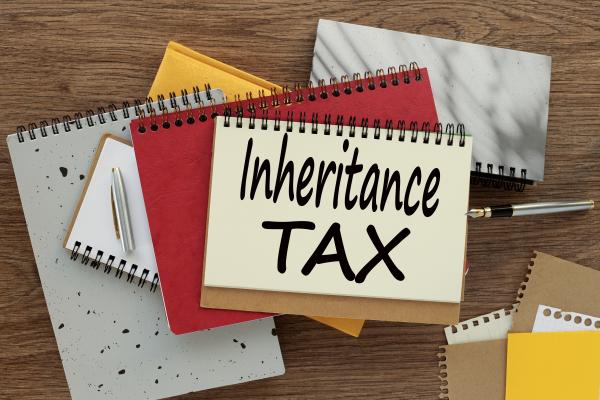 Notebooks and calendar on a desk, with a notepad on top with "Inheritance Tax" written on it