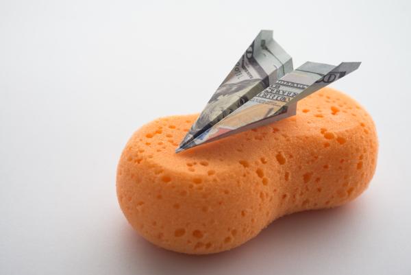Paper aeroplane made of bank note resting on a bath sponge