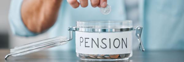 Hand putting a coin in a glass jar labelled pension