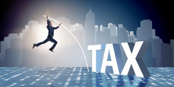 Image of businessman jumping over the word tax