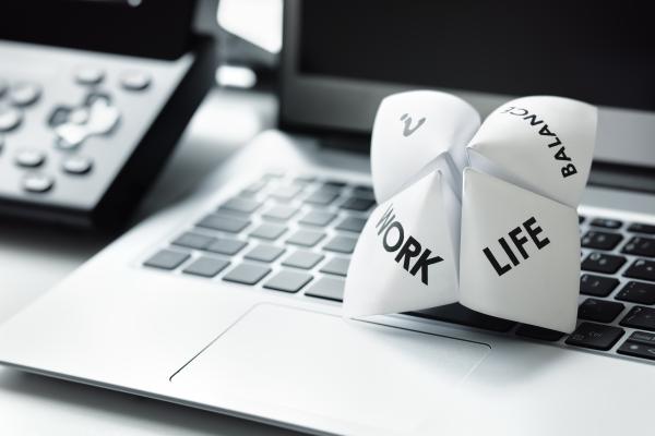 A folded paper with the words work, life, balance and a '?' resting on a computer keyboard