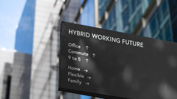 A black sign outside an office reading 'hybrid working future' with the options, office, commute and 9 to 5 underneath