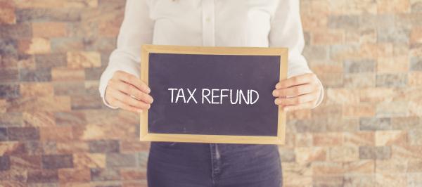 Person holding sign with the words Tax Refund written on it