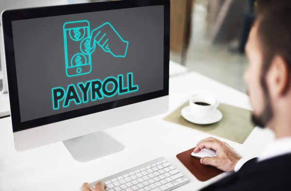 Desktop computer with the word payroll and money graphic on the screen 