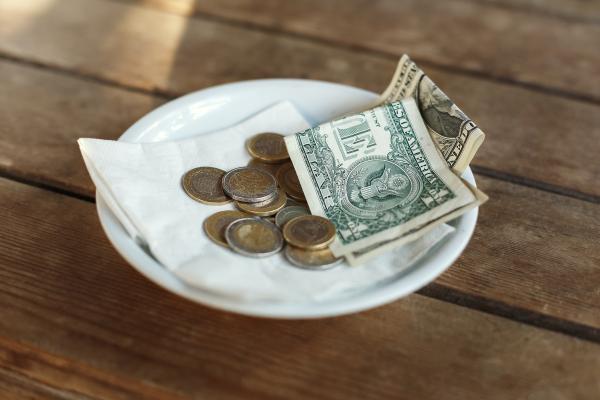 Coins and bank notes left on saucer as a tip