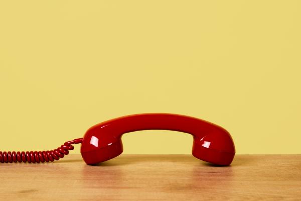 Red phone handset resting on a desk