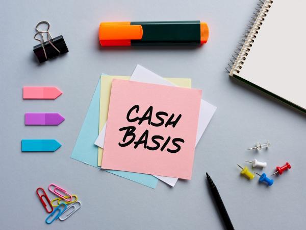 cash basis on sticky note surrounded by stationary