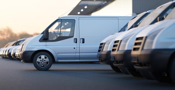 A row of white vans, with one van pulled ahead of the others