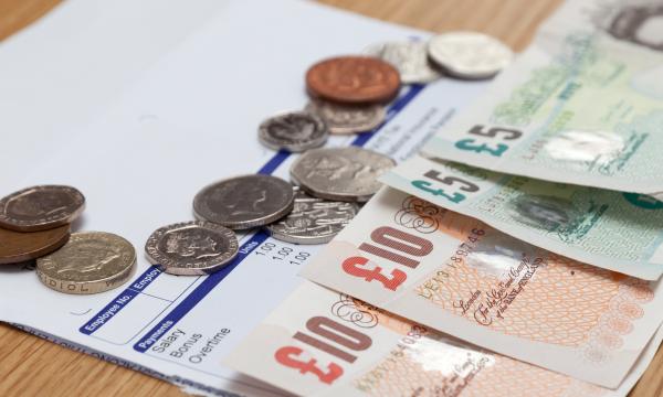 Payslip on desk with coins and banknotes