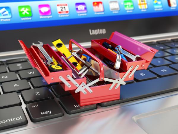 Laptop with miniature metal toolbox open on the keyboard