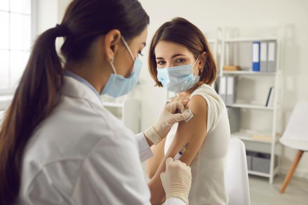 Medical professional delivering injection into a female patient's arm