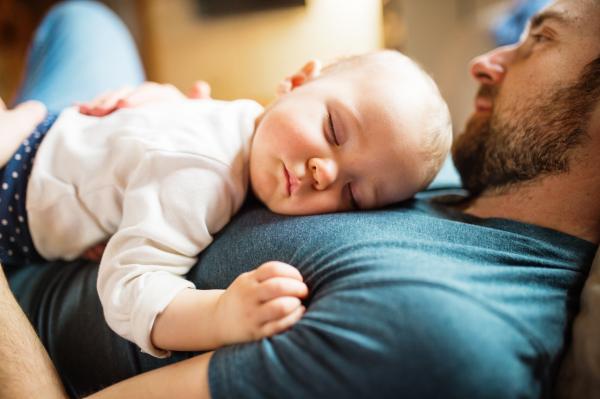 Man laid on his back with baby on his chest