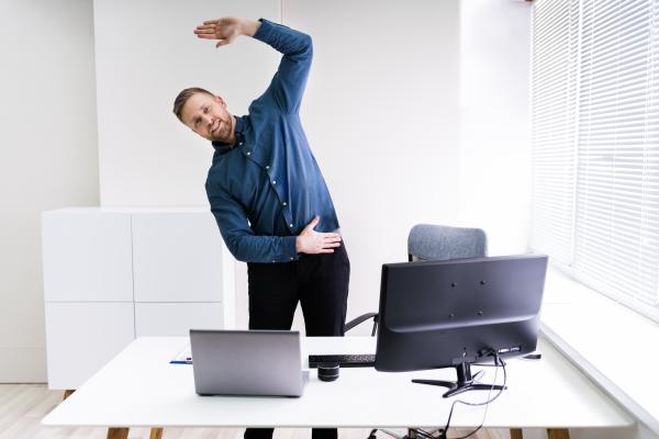 Man stood behind work desk doing exercises