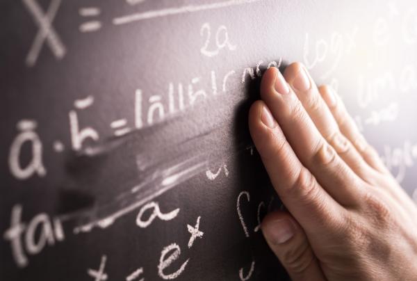 Hand rubbing out chalk writing on a blackboard  