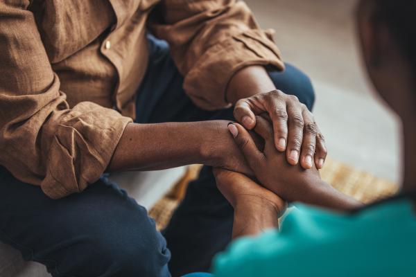 Two people sat opposite each other holding hands