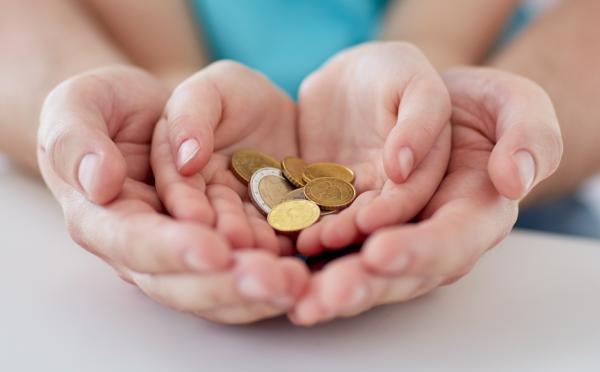 Child's open hands holding money, cupped by adult's hands