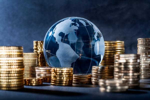 Piles of coins surrounding a digital rendering of planet earth