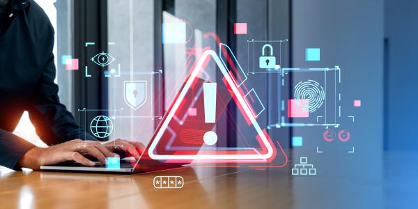Person using laptop with large red warning sign projected over the top, surrounded by digital security images