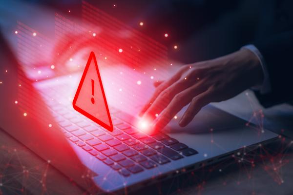 Hands using laptop with a superimposed red warning triangle and red glow
