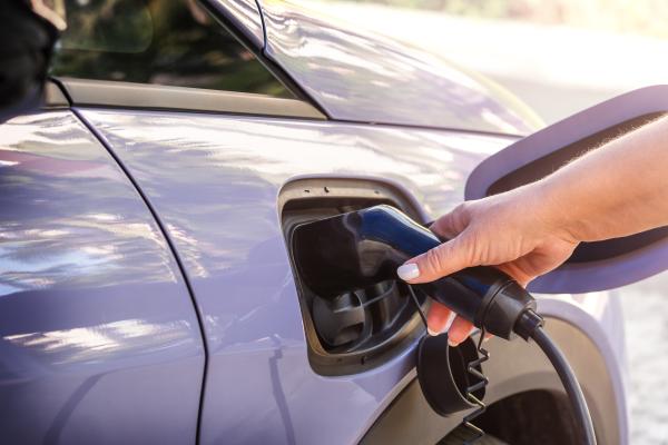 Hand plugging a charging cable into an electric vehicle 