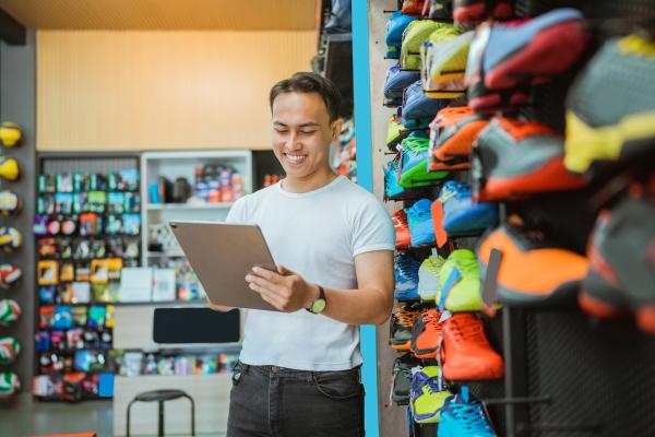 Retail worker stood in a sports store using a tablet computer