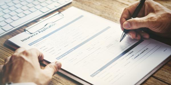 Image shows a person completing an insurance application form