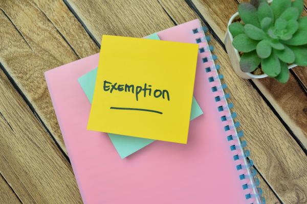 Image shows a pile of notepads with Exemption written on the top