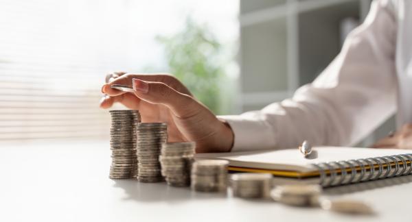 Woman stacking coins onto neat piles of increasing size on a desk