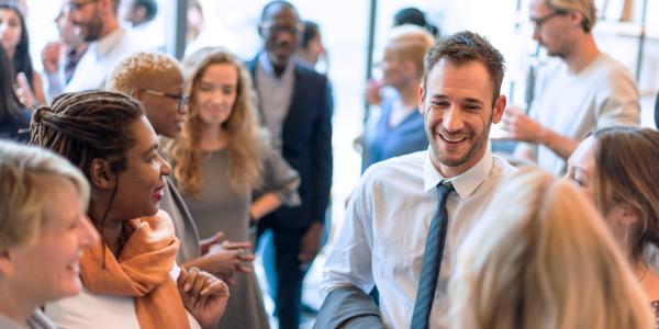 Busy room of people in business attire talking and smiling