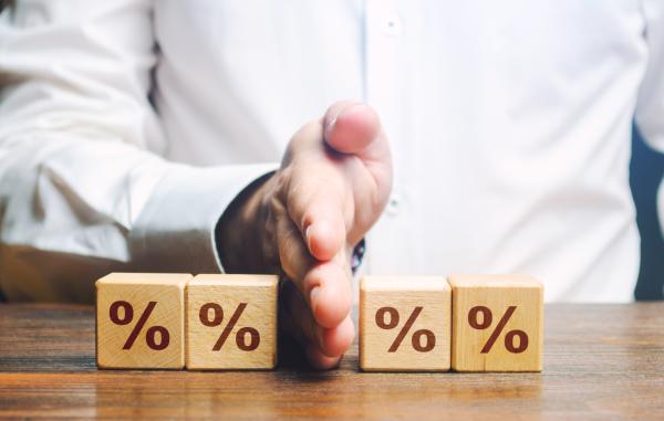 Four wooden blocks on a desk with percentage signs on, with a man's hand dividing the row in half