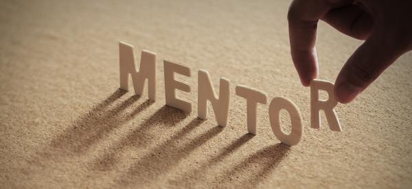 The word mentor with a hand placing the R at the end