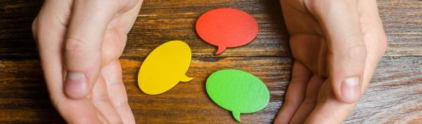 Hand surrounding multicoloured speech bubbles