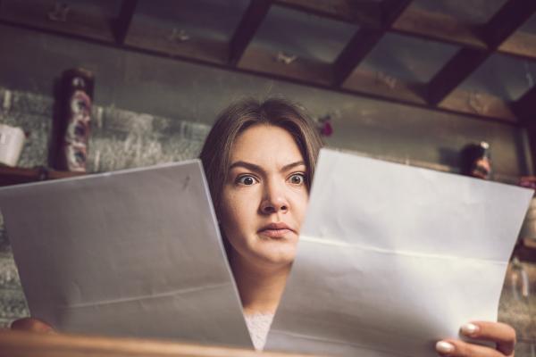 A lady holding up two letters and looking confused 