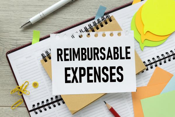 Various stationery on a desk, with notepaper on top reading "reimbursable expenses"