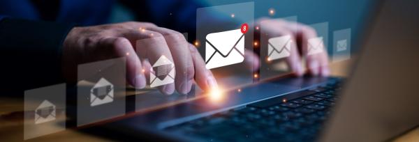 Hands typing on laptop with email message icons overlaid
