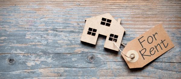 wooden cut out of house with brown luggage label attached stating for rent