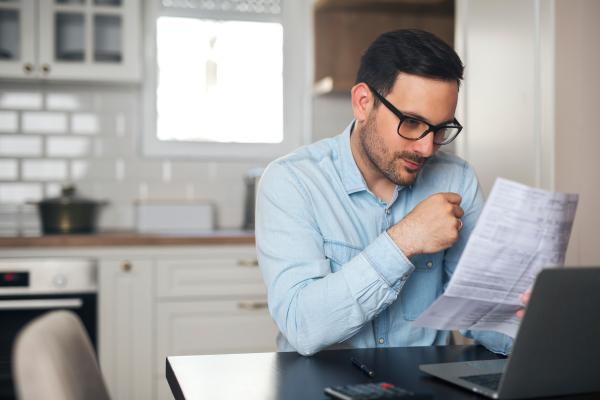 A man is working from home and is sitting in the kitchen