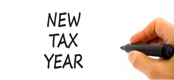 Hand holding a black marker pen next to handwritten text "New Tax Year" 