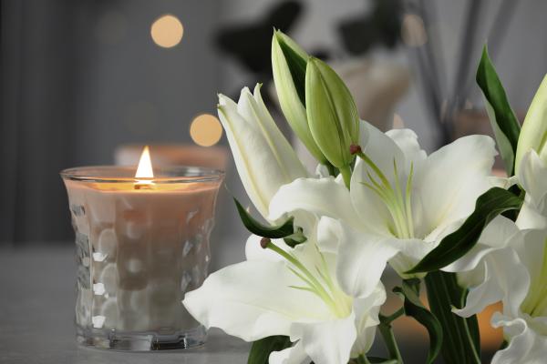 A candle burns next to a bunch lilies to signify bereavement 