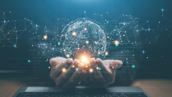 Hands outstretched together over a laptop, palms up, with a virtual globe appearing within the cupped hands