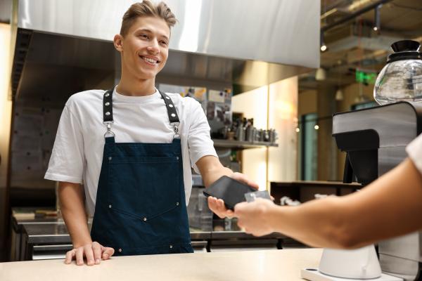Cashier in a cafe or restaurant taking customer's payment  using a digital card reader