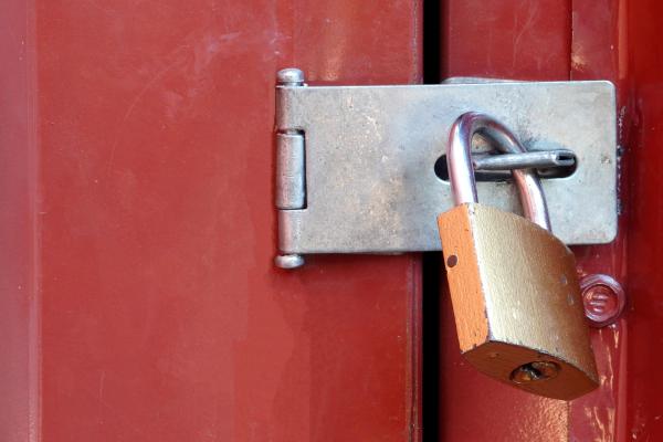 A padlock holds a large red door shut 