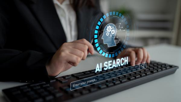 Person using a computer keyboard, with virtual graphics reading "AI Search" projected above it