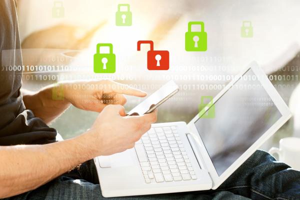 A person is holding a mobile phone and trying to log into their laptop 