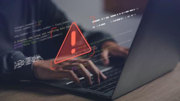 Person using a laptop with virtual graphics projected over the top, the biggest being a red warning triangle